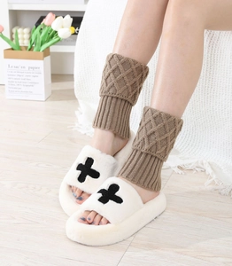 Detail of brown cable knit leg warmers with diamond pattern and plush cross slippers