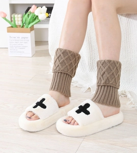 Detail of cable knit leg warmers in coffee brown paired with plush thick-soled slippers