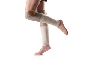 Close-up of ribbed knit leg warmers with fuzzy pompom details in beige and brown
