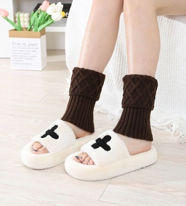 Detail of dark brown argyle knit leg warmers paired with cream plush slippers