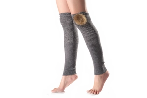 Close-up of grey ribbed knit leg warmers with detachable brown faux fur pom poms