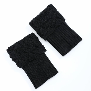 Detailed view of black knitted boot cuffs with floral crochet and ribbed texture