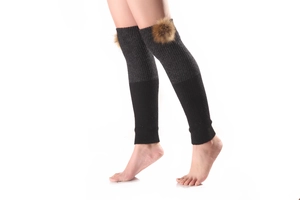 Close-up of knit leg warmers with bicolor grey-black design and brown pom pom details