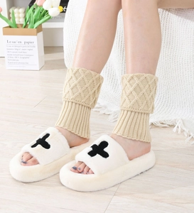 Detail of beige diamond-patterned knit leg warmers paired with plush fuzzy slippers