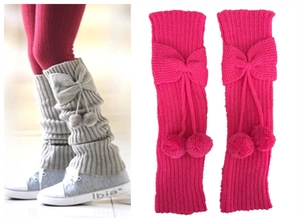 Detail of knitted leg warmers with bows and fuzzy balls in grey and rose red colors