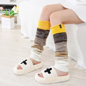 Détail de jambières tricotées à rayures avec boutons et pantoufles en peluche dans un intérieur