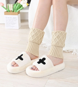 Detail of khaki diamond-pattern knit leg warmers paired with plush cross slippers