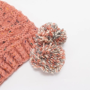 Detail der Strickstruktur bei der lachsrosa Mütze mit bunten Sprenkeln und Bommeln