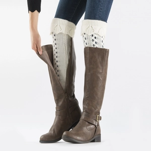 Close-up of white knitted leg warmers with hollow mesh pattern worn with brown tall boots