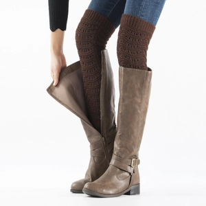 Detail of dark brown knit leg warmers with cutout patterns paired with tall leather boots