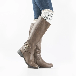 Detail of brown leather tall boots with metal buckle strap and white lace leg warmers