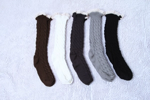 Détail de la maille torsadée et bordure en dentelle blanche sur jambières de couleurs