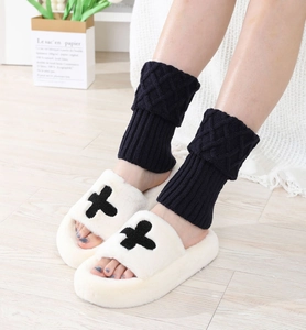 Detailed view of knitted leg warmers with diamond pattern and plush open-toe slippers