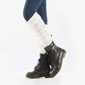 Detail of white crochet knit leg warmers showing intricate hollow lace patterns and scalloped edges