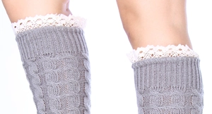 Détail de jambières grises en maille torsadée avec dentelle blanche et motif épais