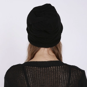 Close-up of the back view of a black knitted beanie with textured ribbed patterns