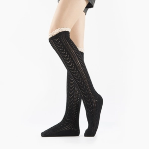 Detail of black crochet leg warmers with delicate white lace trim and mesh knit texture