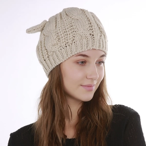 Detail of cream cable knit beanie with cute cat ears and thick textured pattern