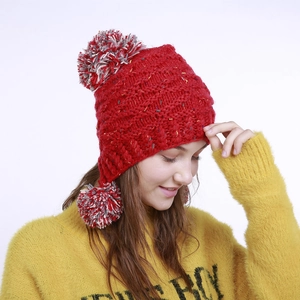 Nahaufnahme der roten Strickmütze mit bunten Tupfen und flauschigem Bommel