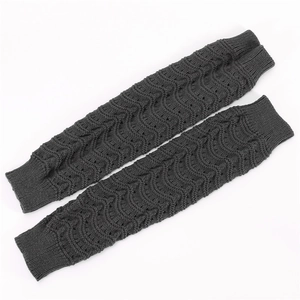 Detail showing dark grey knitted leg warmers with delicate wavy patterns and ribbed cuffs