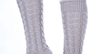 Gros plan sur des jambières grises en tricot torsadé montrant les détails de la laine
