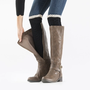 Detail of black lace trim knitted leg warmers styled with dark brown leather boots