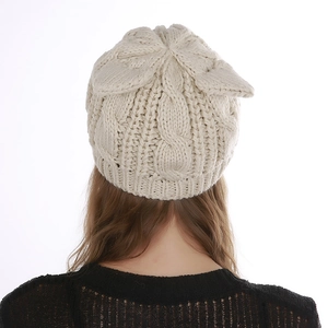 Detail of cable knit pattern and cat ears on a beige winter beanie shown from the back