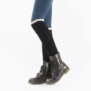 Macro shot of black knitted leg warmers with delicate white lace trim and ribbed texture