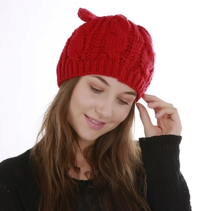 Detail of red cable knit beanie featuring cute cat ear design and thick winter texture
