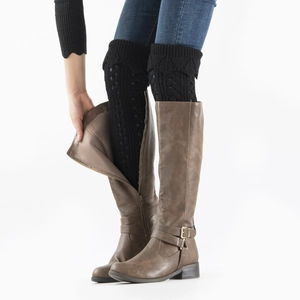 Detail of black hollow-out knitted leg warmers styled with stylish leather boots