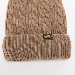 Close-up of khaki cable knit beanie featuring a black woven label with golden logo