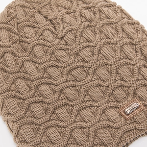 Makro-Detail der khakifarbene Strickmütze mit Korbmuster und modischem Lederetikett