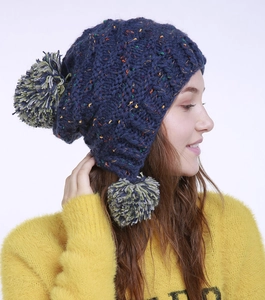 Detailaufnahme der dunkelblauen Strickmütze mit bunten Punkten und drei Bommeln
