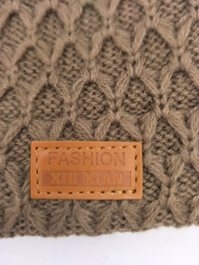 Detalle macro del gorro de punto marrón oscuro con diseño de rombos y etiqueta de cuero