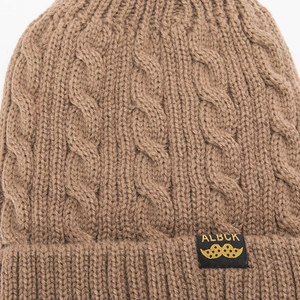 Close-up of the brown cable knit texture and woven label on this winter beanie hat