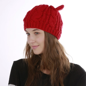 Detailed knit texture of red beanie with cable pattern and unique pointed top design