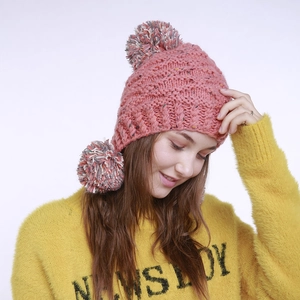Detaillierte Strickstruktur und weiche Pompons an einer rosa Ohrenklappenmütze