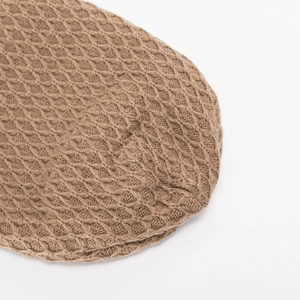 Detalle macro de un gorro de punto marrón con textura gruesa de patrón de panal en 3D