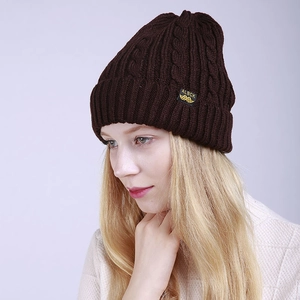 Detailed knit texture of dark brown beanie featuring classic cable stitch and logo tag