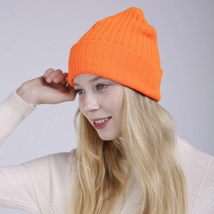 Detail of bright orange knitted beanie with classic ribbed texture and folded cuff