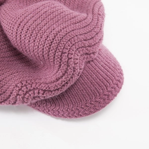 Detail view of the thick knit texture and peak brim of this warm pink winter beanie hat