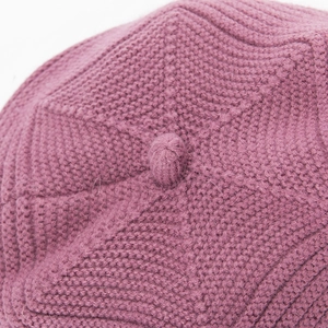 Macro detail of purple knitted beret showing thick yarn texture and top pom-pom decor