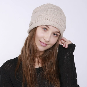 Detailed knit texture of beige slouchy beanie with decorative hollow metal eyelets