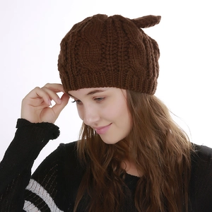 Close-up of thick cable knit texture and cat ear detail on a brown winter beanie