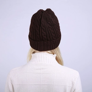 Detail view of the back of a dark brown cable knit beanie with thick woolen texture