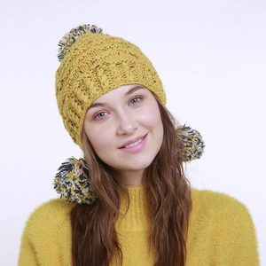 Detail der gelben Strickmütze mit Ohrenklappen und drei bunten Pompons für den Winter