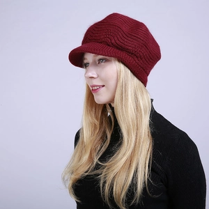 Detail view of burgundy knitted peak cap featuring thick wavy texture and short visor
