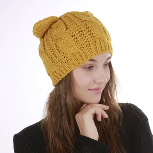 Detailed close-up of a yellow chunky knit beanie featuring cute cat ear design and twist pattern