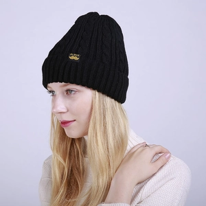 Detailed view of black cable-knit beanie featuring a woven label with ALBCK branding