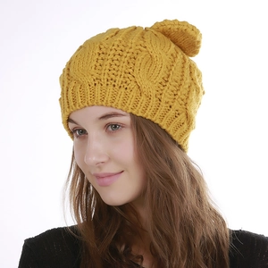 Detail of ginger yellow cable knit beanie with faux fur pom pom and thick wool texture